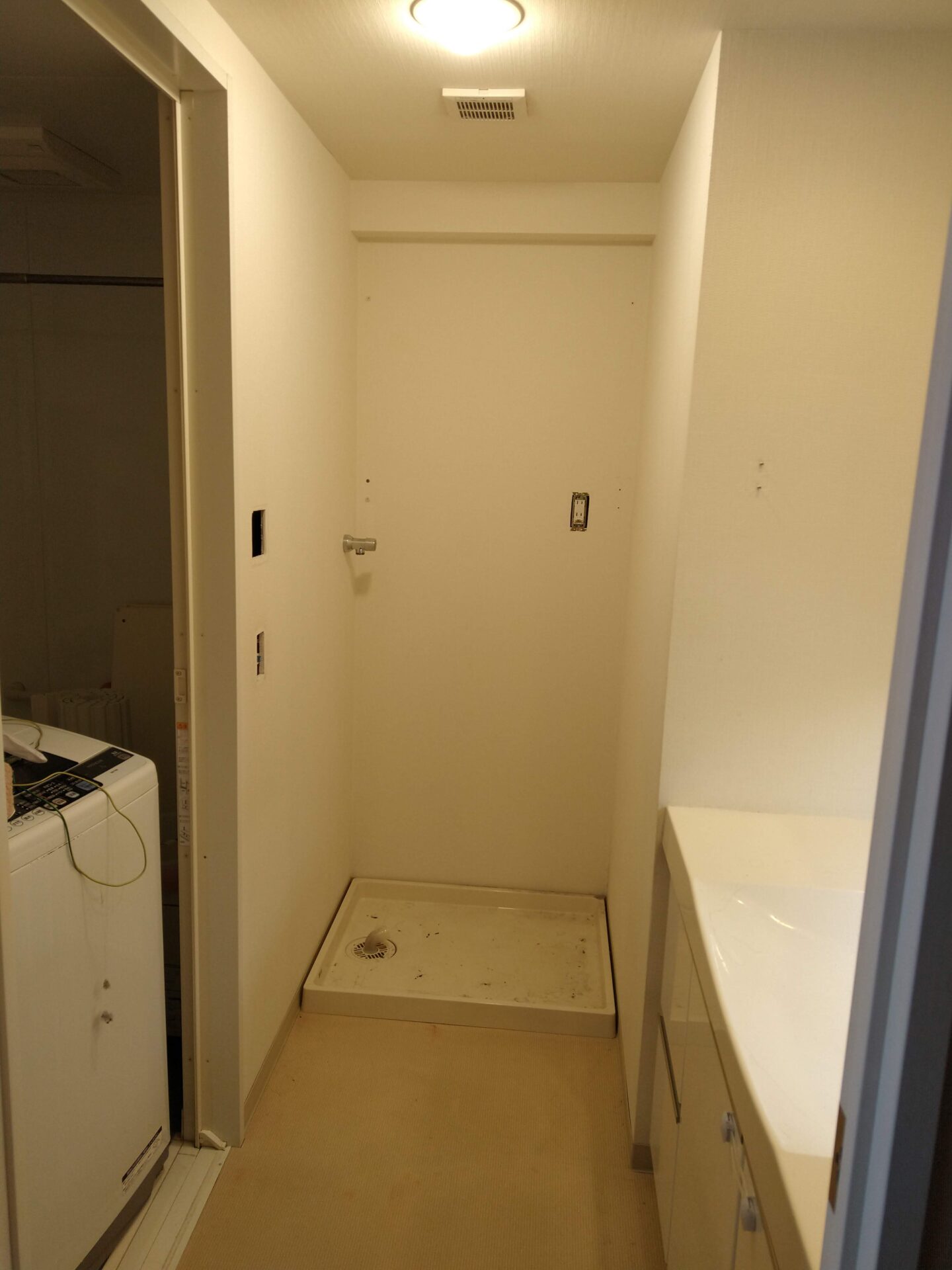 我が家の洗濯機置き場の交換前。通常タイプの洗濯パンと洗濯水栓、コンセントが写っている