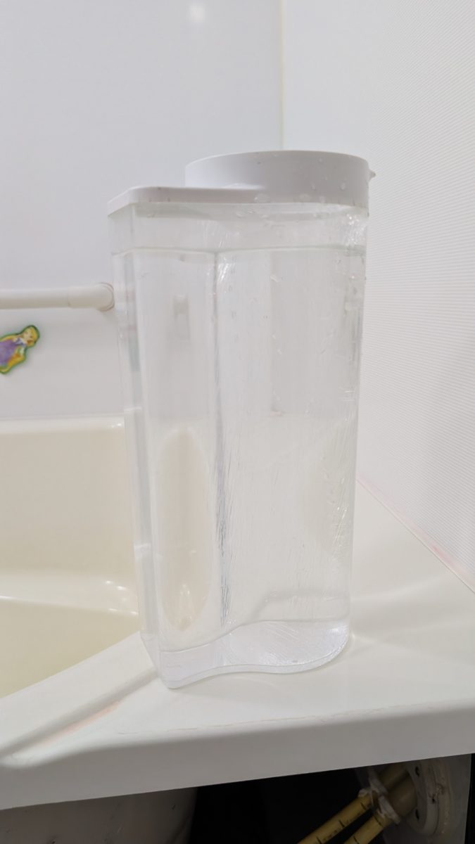 浴槽のふちに置いた、目盛り付きの透明な計量容器