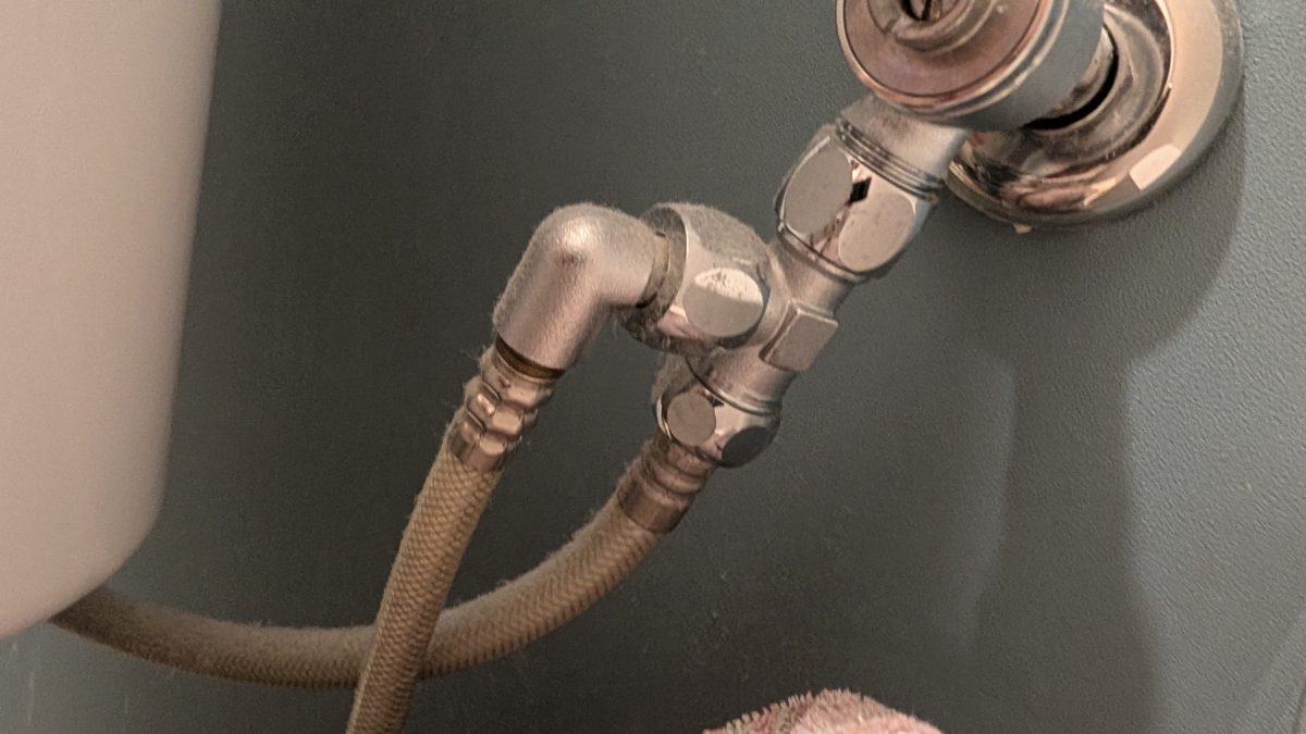 付ける前のトイレの給水。止水栓の先に分岐金具があり、タンク行きとウォシュレット行きのホースに分かれている